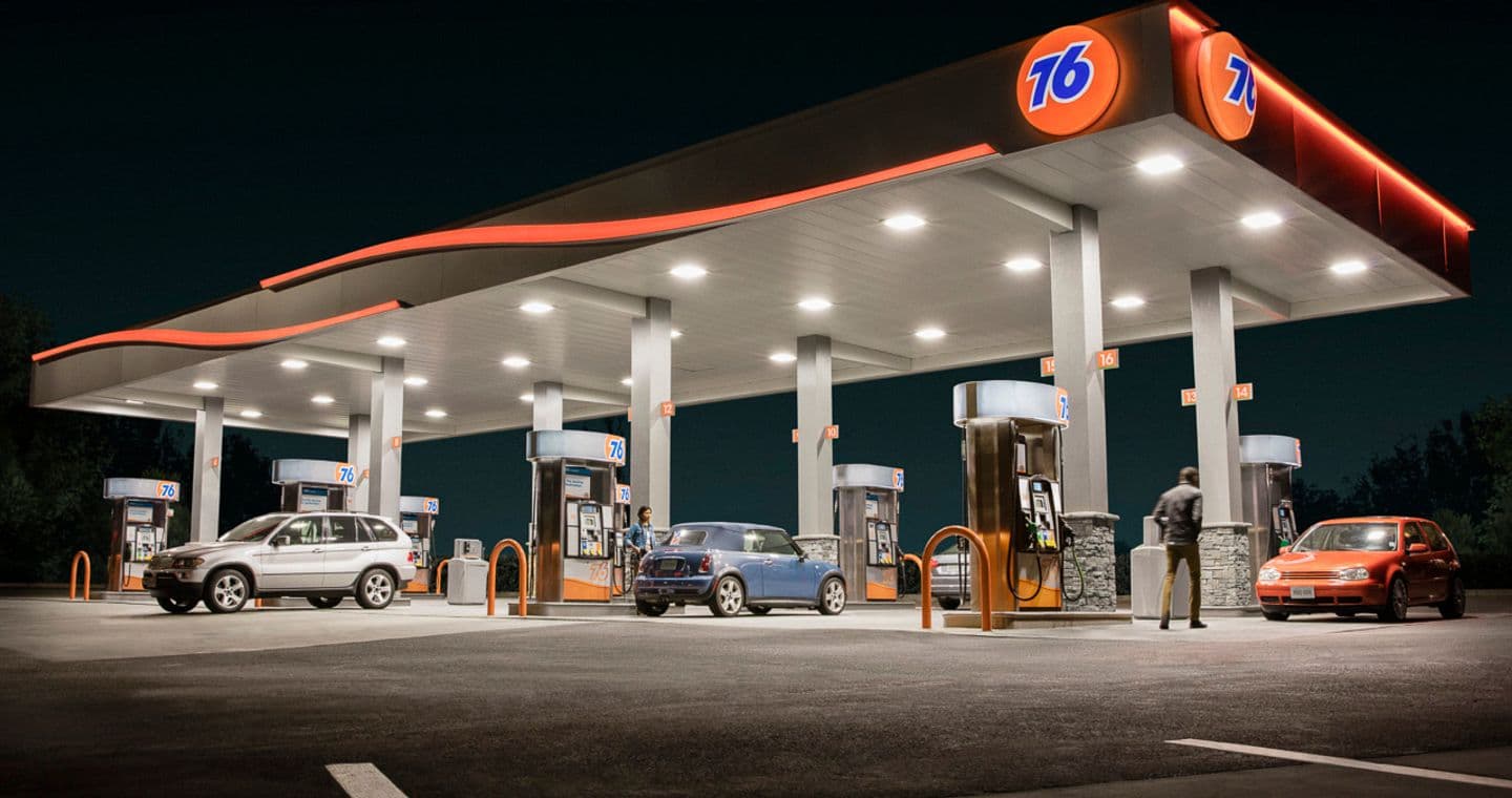 76 station at night with cars at the pumps.
